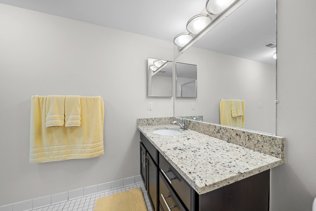 Modern bathroom with large vanity mirror and tub/shower at Lakeside Village Apartments in Clinton Township, MI