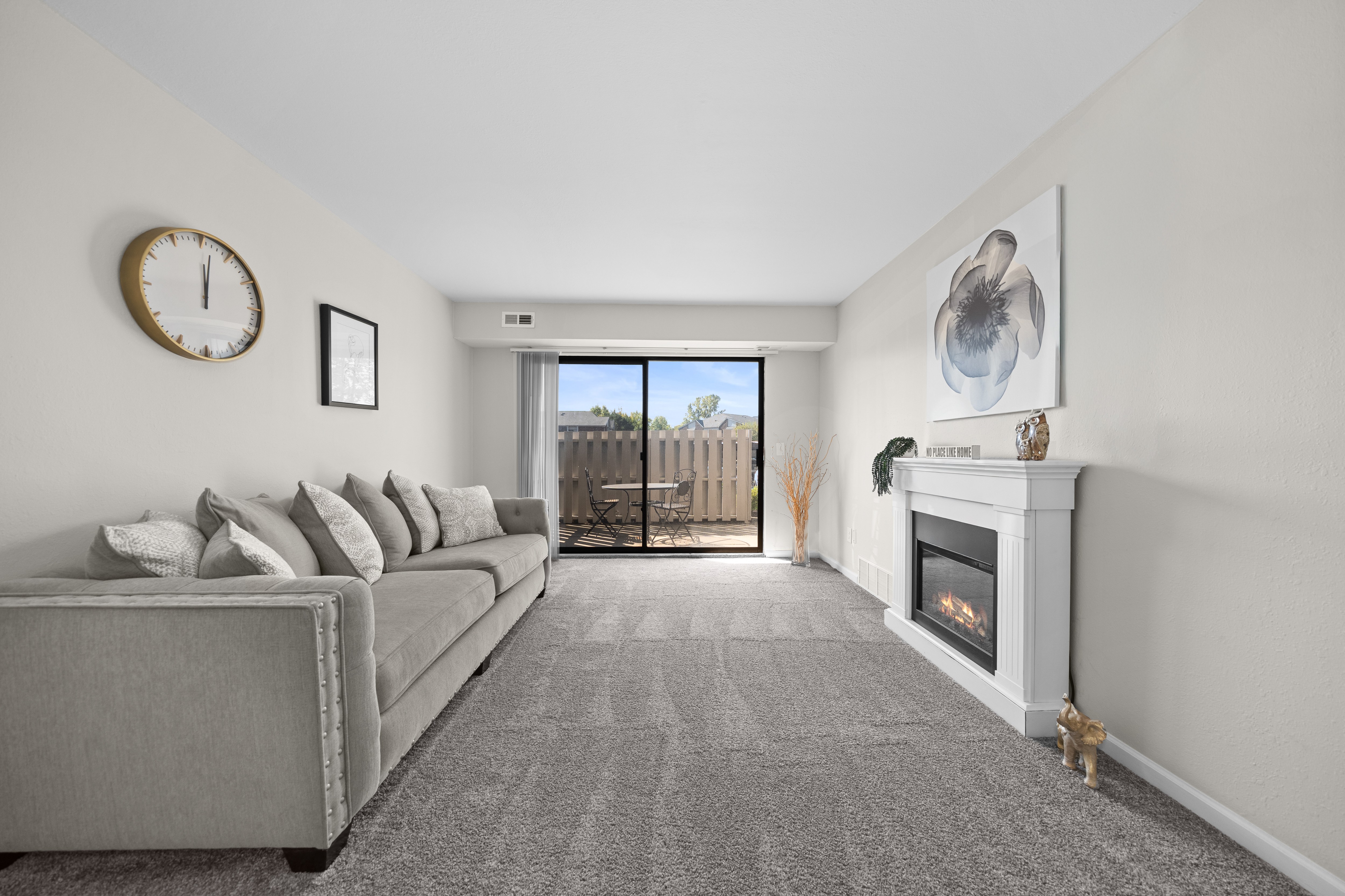 A living room with a grey couch and a fireplace.