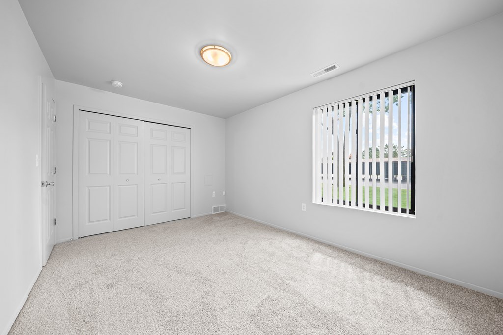 A white room with a door, window, and carpet.