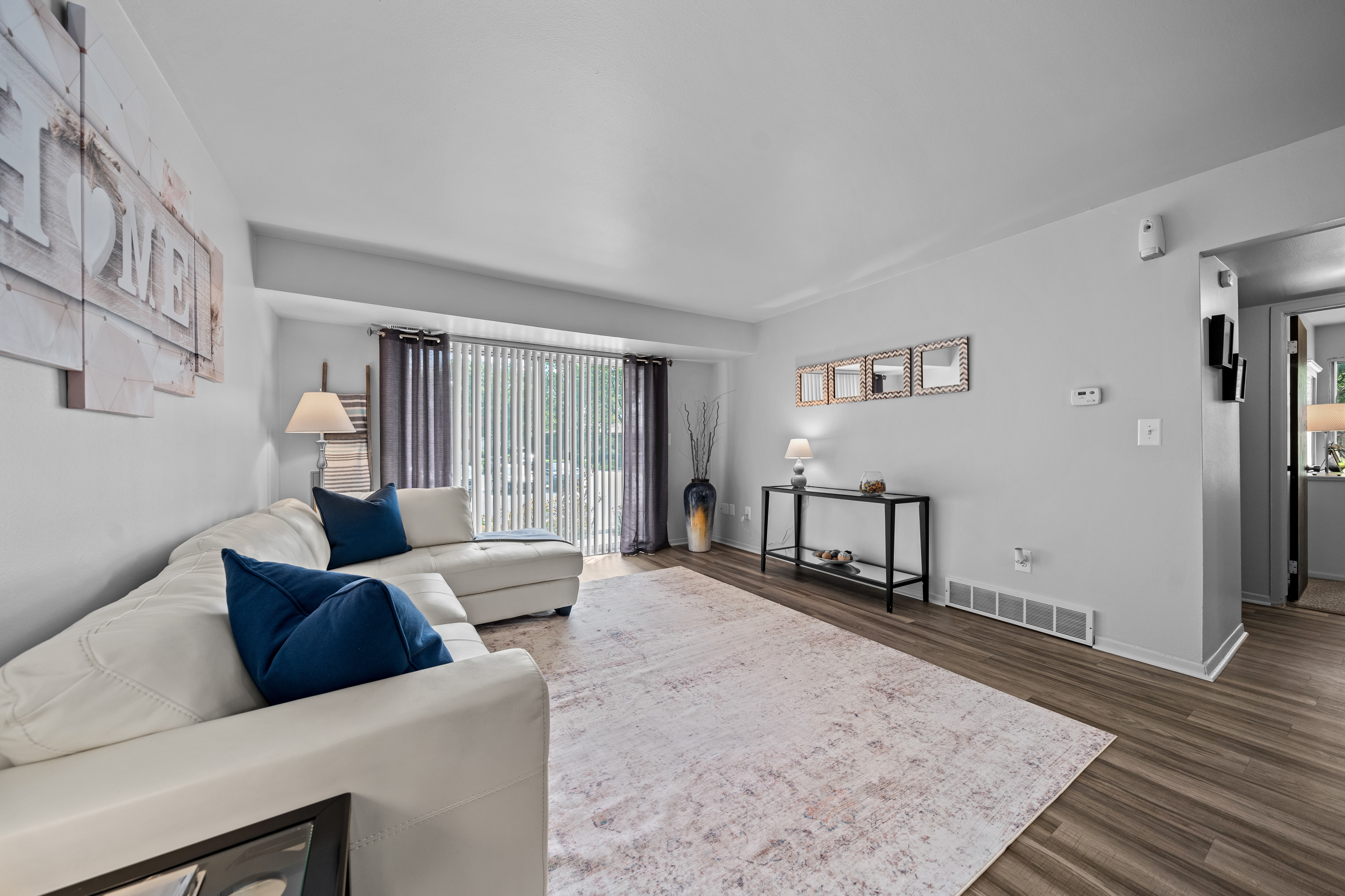 A living room with a white couch and a pink rug.
