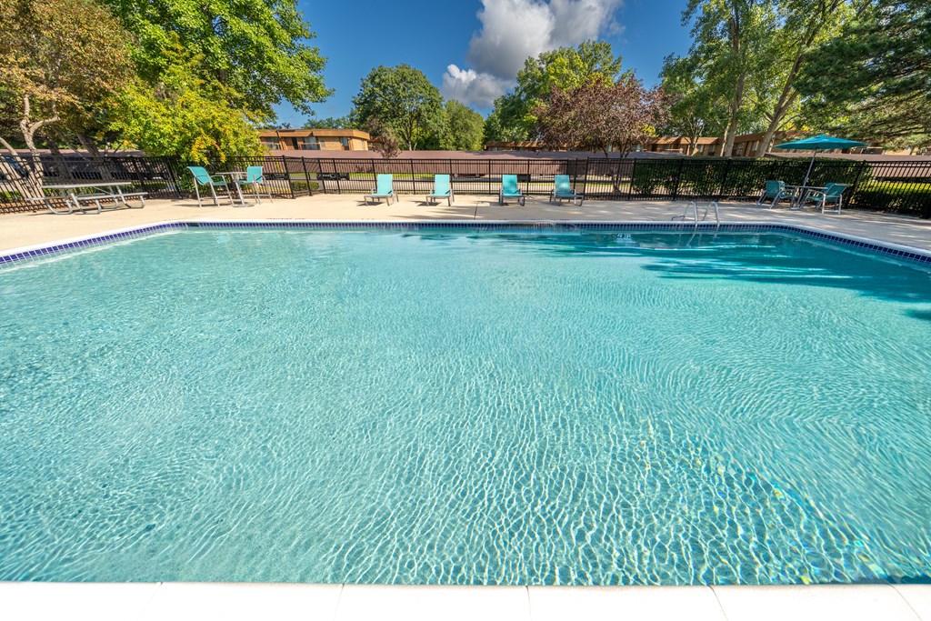 Heated pool equipped with comfy lounge chairs at Westwood Village Apartments in Westland, MI