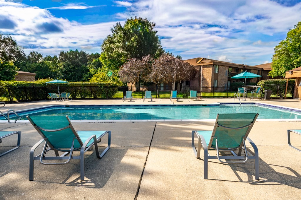 Heated pool equipped with comfy lounge chairs at Westwood Village Apartments in Westland, MI