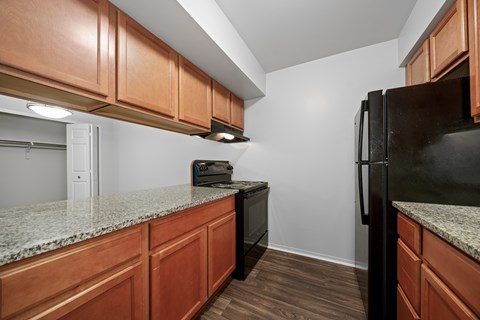 A kitchen with wooden cabinets and a black refrigerator.