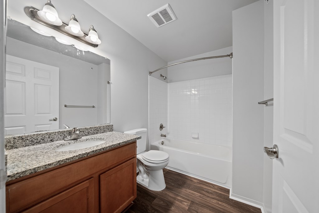 Upgraded bathroom with curved shower rod at Woodland Villa Apartments in Westland, MI.