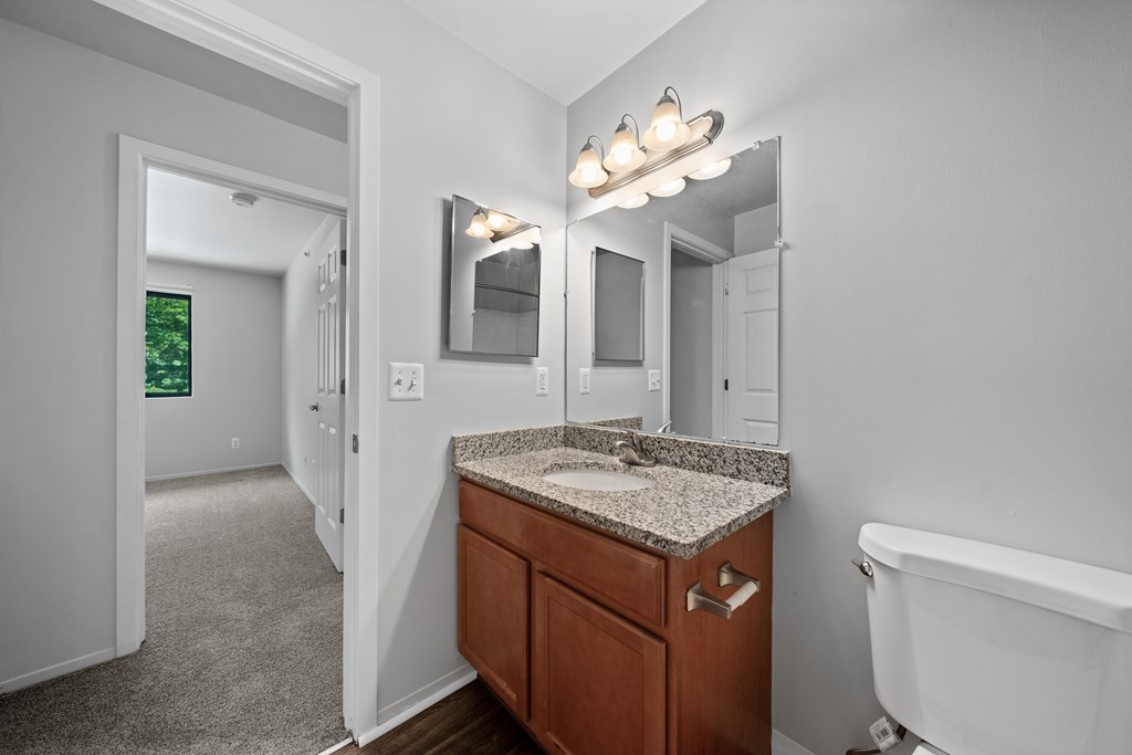 A bathroom with a white tub, a sink, and a mirror.