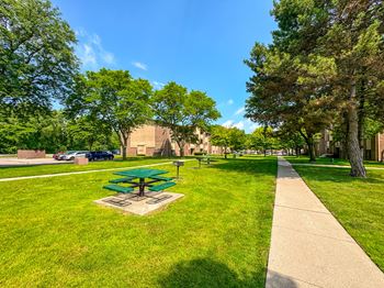 Expansive green space with picnic area at Woodland Villa Apartments in Westland, MI.