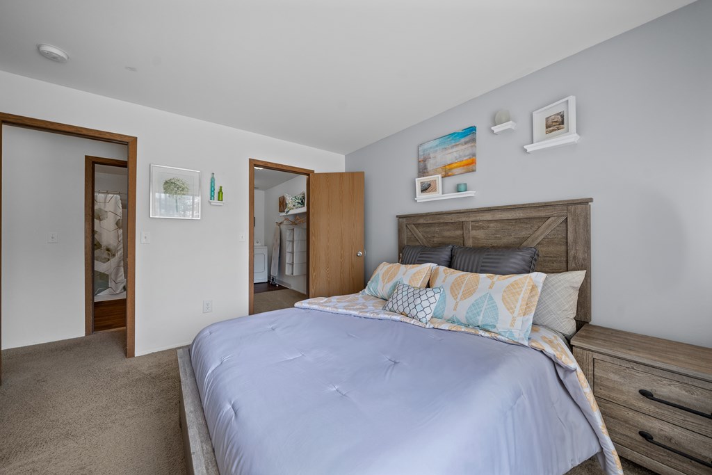 A bedroom with a bed, dresser, and two doors.