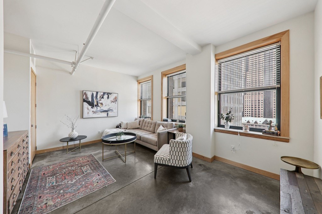 A living room with a rug, a couch, a chair, and a table.