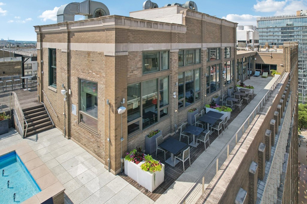 A building with a pool and a balcony with chairs and tables.