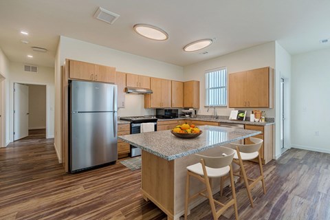 A kitchen with a refrigerator, island, and chairs.