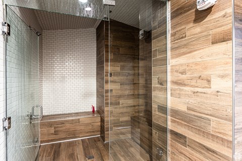 A shower with a glass door and a wooden wall.