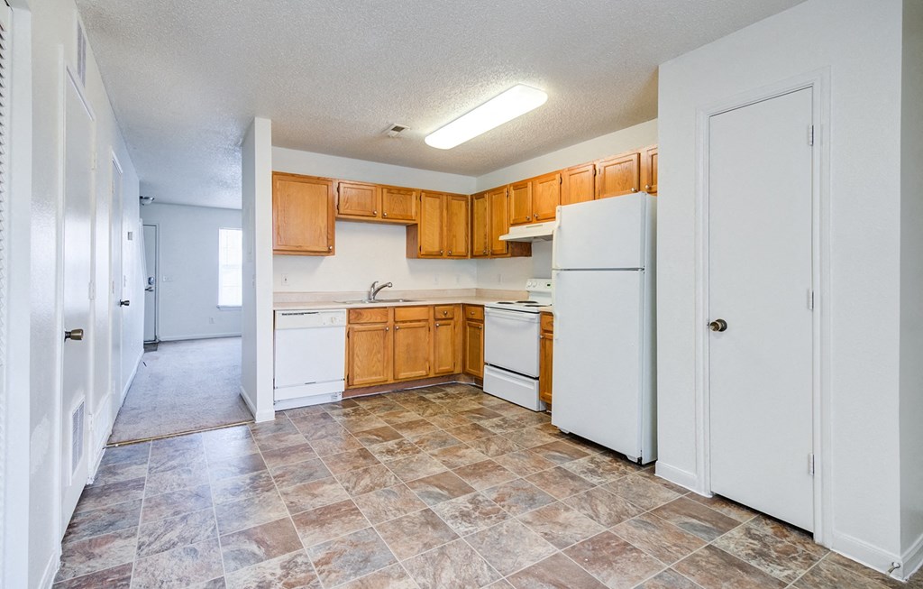 an empty kitchen with white appliances and wooden cabinets at The Bluffs at Cherry Hills, Nebraska