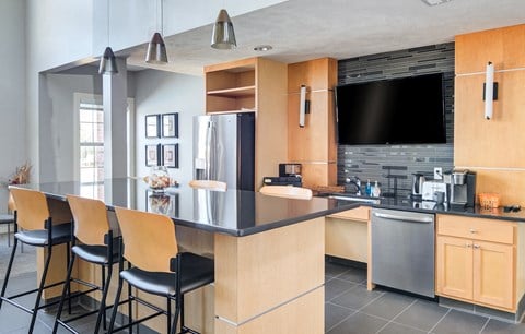a kitchen with a large island with bar stools and a tv in a house