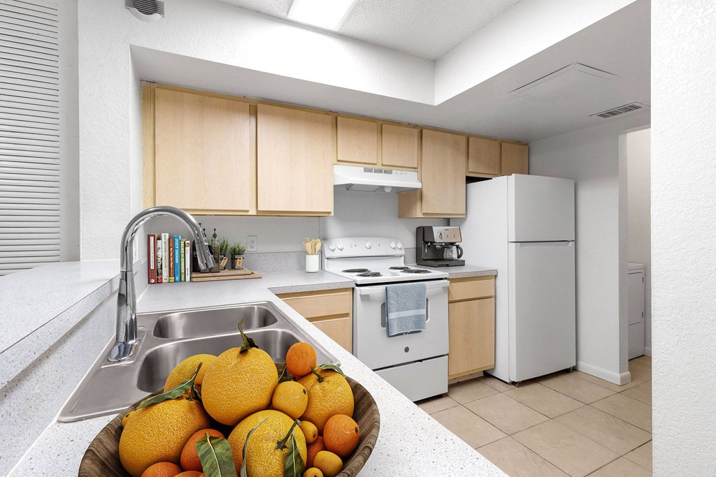 a kitchen with white appliances and a bowl of fruit