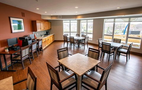 a dining room with tables and chairs and a kitchen with large windows