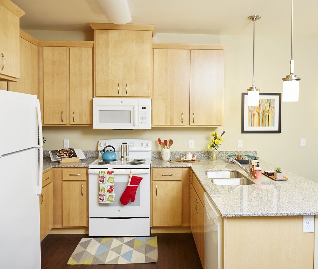  a kitchen with wooden cabinets and a granite countertop at The Cambric Senior Apartments, St. Paul, 55106