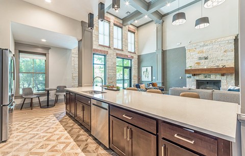a large kitchen with a large counter top and a living room with a fireplace
