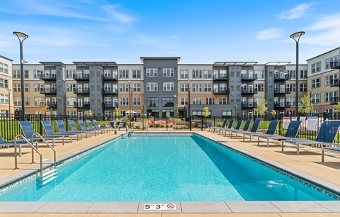 an apartment swimming pool with an apartment building in the background