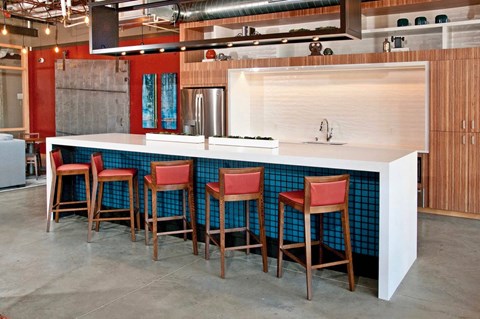 a kitchen with a row of chairs at a counter