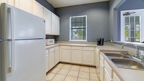 an empty kitchen with white cabinets and a refrigerator