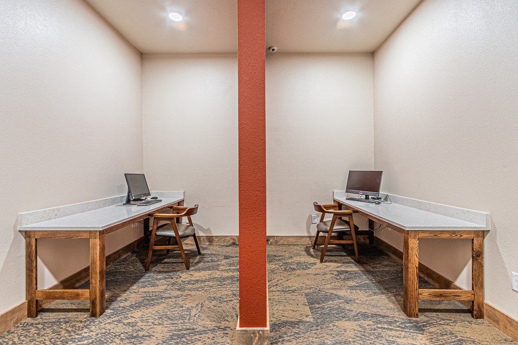 a writers room with two tables with computers and chairs