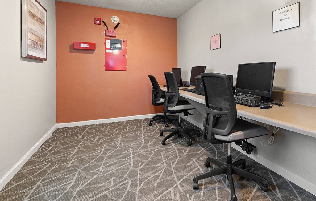 a computer room with desks and chairs and a bulletin board on the wall