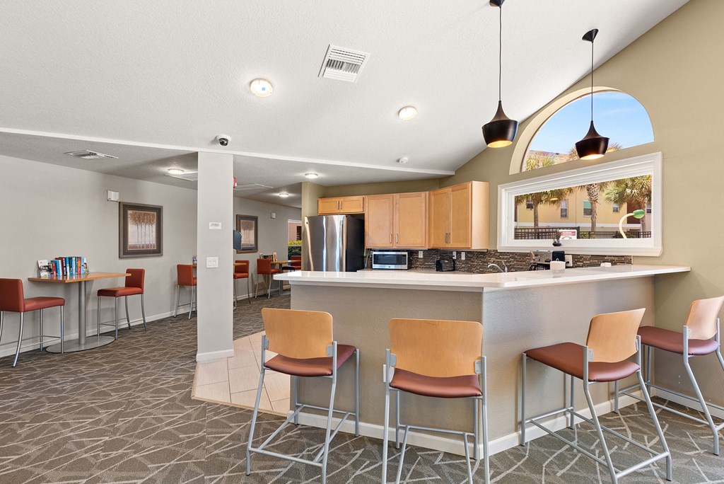 a clubhouse with a bar and a kitchen with stools