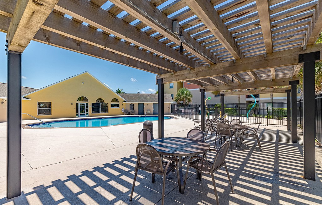 a patio with tables and chairs next to a swimming pool