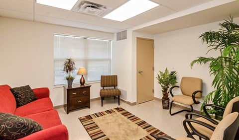 a living room with a red couch and chairs and a window