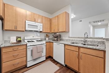 a kitchen with white appliances and granite counter tops and wooden cabinets at Sandy Creek Apartments, Bryan, Texas