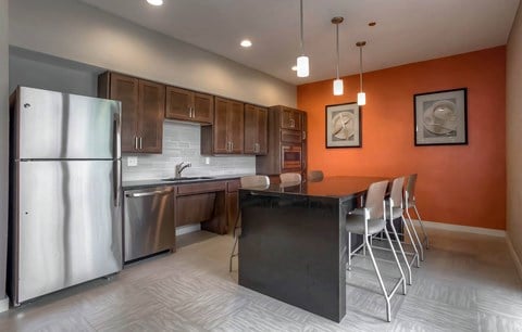 a kitchen with stainless steel appliances and a bar with chairs