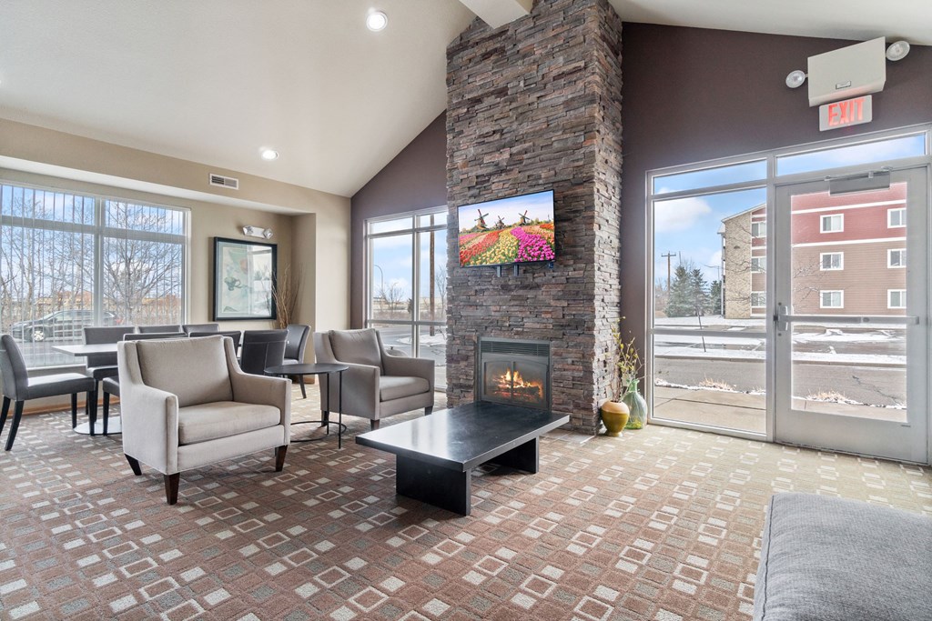a lobby with couches chairs and a fireplace    and a glass door