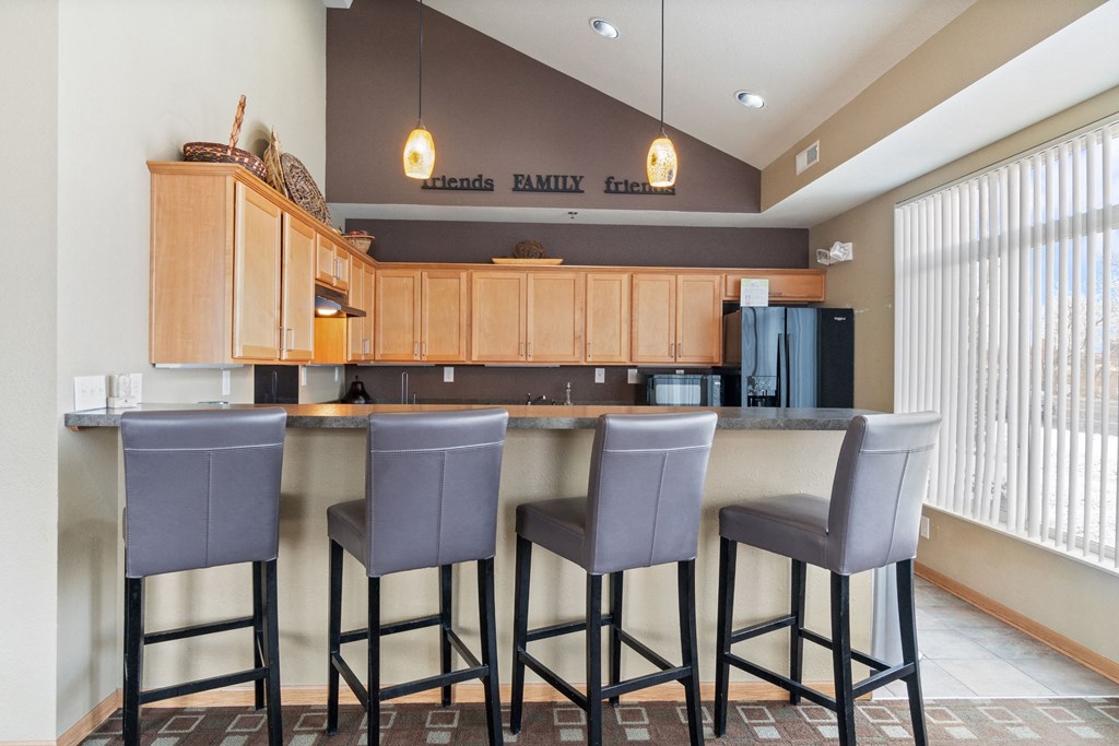 a kitchen with three bar stools in front of a counter with three chairs