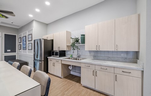 A kitchen with a white table and chairs, a refrigerator, a sink, and cabinets.