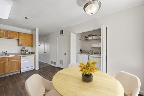 A kitchen with a table and chairs in the foreground and a laundry room in the background.