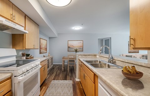 A kitchen with a white stove top oven and a white sink.