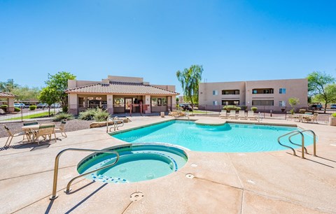 A large swimming pool with a slide in the middle of a sunny day.