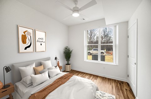 A bedroom with a bed, pillows, a ceiling fan, and two framed pictures on the wall.