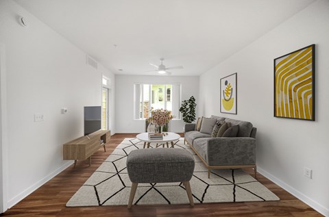 A living room with a grey sofa, a grey ottoman, a wooden bench, a coffee table, and a painting on the wall.