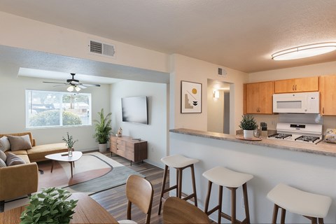A well-lit kitchen with a bar area and a living room with a couch and a coffee table.