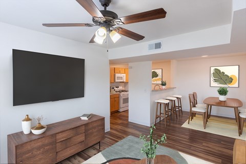 A living room with a ceiling fan and a black wall hanging.
