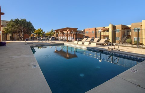 A swimming pool in front of a building with a clear blue sky.