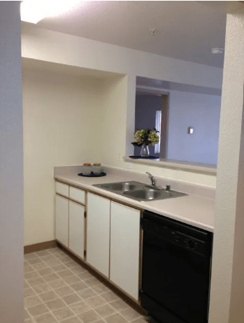 A kitchen with white cabinets and a black dishwasher.