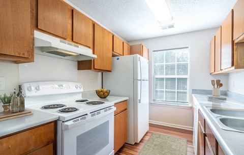 A kitchen with a white stove top oven and white refrigerator.