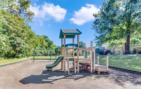 A playground with a green slide and a wooden structure.