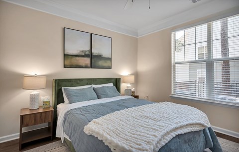 A bedroom with a large bed and two lamps on side tables.