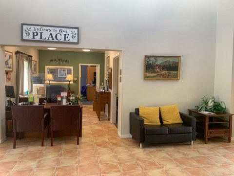 A living room with a couch, chairs, and a painting on the wall.
