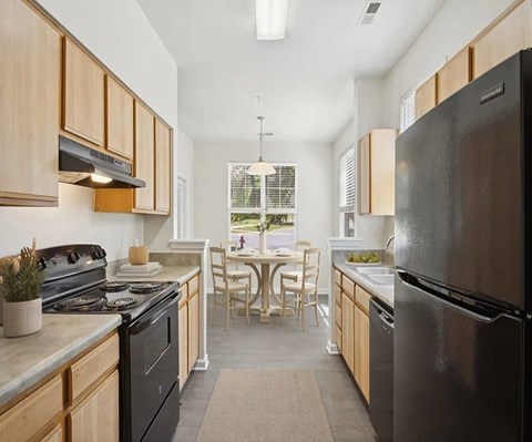 A kitchen with a black refrigerator and wooden cabinets.