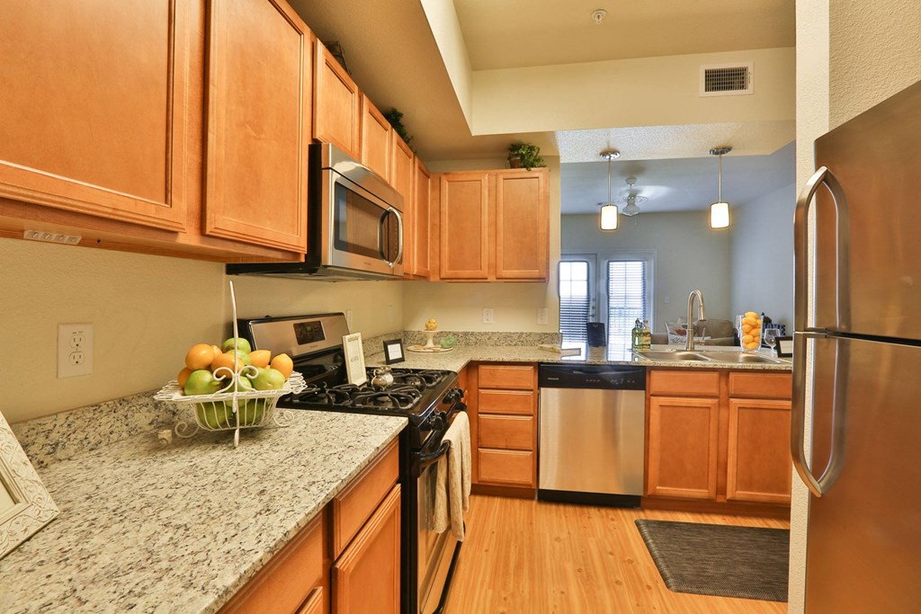 a kitchen with wooden cabinets and granite counter tops at Mariposa at Cedars of Elk Drive 55+ Apartments, Burleson
