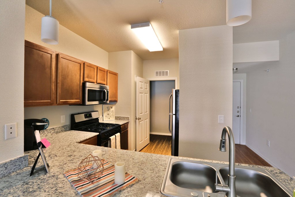a kitchen with granite counter tops and a stainless steel refrigerator at Cedars of Elk Drive 55+ Apartments, Texas, 76028